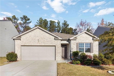 Single story home featuring brick siding, driveway, an attached garage, and a front yard