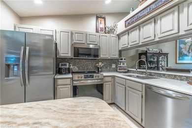 Kitchen featuring stainless steel appliances, decorative backsplash, light countertops, recessed lighting, and gray cabinetry