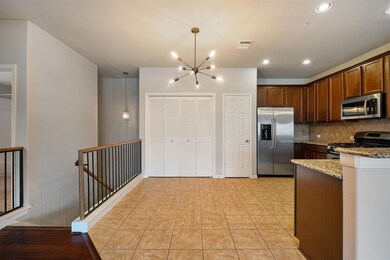 Kitchen featuring light stone counters, tasteful backsplash, appliances with stainless steel finishes, a chandelier, and light tile patterned flooring