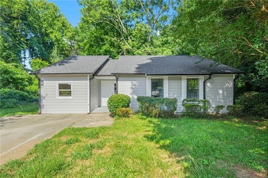 Ranch-style home with roof with shingles, a front lawn, and driveway