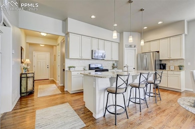 Kitchen featuring a center island with sink, stainless steel appliances, a breakfast bar, and light wood-type flooring