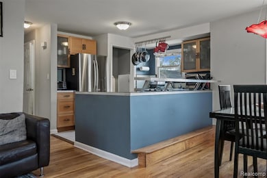 Kitchen featuring glass insert cabinets, freestanding refrigerator, light wood-style flooring, and a peninsula