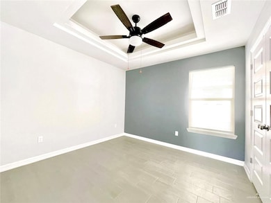 Unfurnished room featuring a tray ceiling and a ceiling fan
