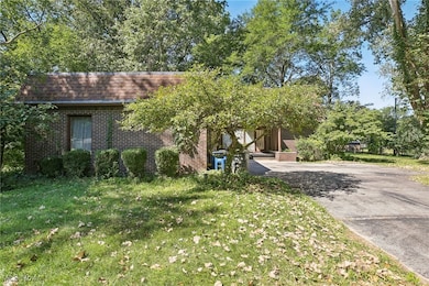 View of front of home featuring brick siding, a front lawn, roof with shingles, and mansard roof