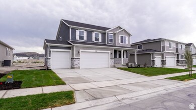 View of front facade featuring covered porch, an attached garage, driveway, a front yard, and stone siding