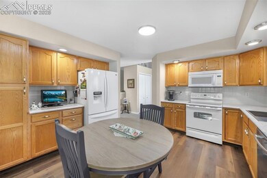 Kitchen featuring white appliances, light countertops, and backsplash