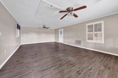 Spare room featuring attic access, ceiling fan, wood finished floors, and crown molding