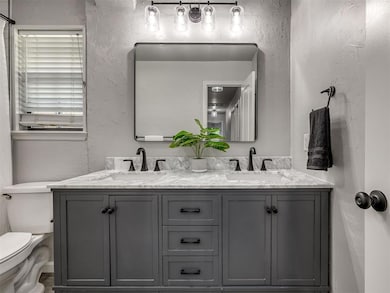 Bathroom featuring double vanity and a textured wall