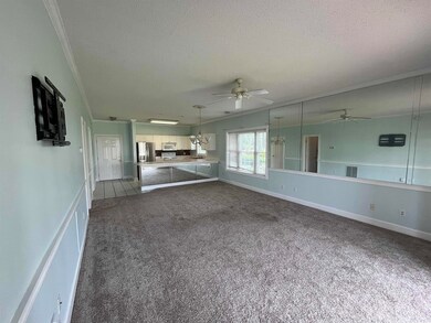 Unfurnished living room with a ceiling fan, dark colored carpet, a textured ceiling, and crown molding