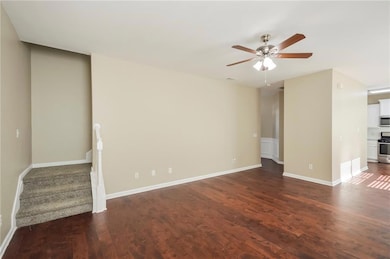 Unfurnished living room with ceiling fan, dark woo