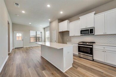 Kitchen with appliances with stainless steel finishes, white cabinetry, decorative backsplash, recessed lighting, and a kitchen island