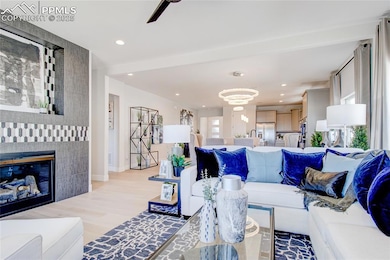 Living room with healthy amount of natural light, light wood finished floors, recessed lighting, a glass covered fireplace, and ceiling fan