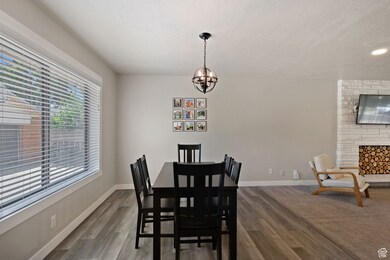 Dining room with dark wood finished floors, a fireplace, a chandelier, and a textured ceiling
