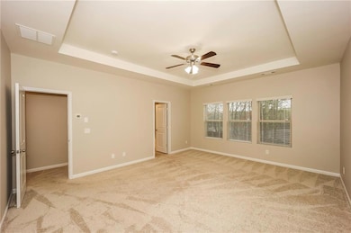Unfurnished room with a raised ceiling, light carpet, a ceiling fan, and baseboards