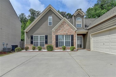 View of front of house with brick siding, driveway, central air condition unit, and an attached garage