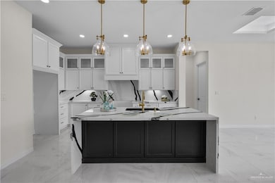 Kitchen featuring light marble finish floors, recessed lighting, white cabinets, a spacious island, and light countertops
