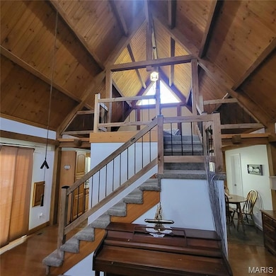 Stairs featuring a wood ceiling with exposed beams, wood finished floors, and high vaulted ceiling