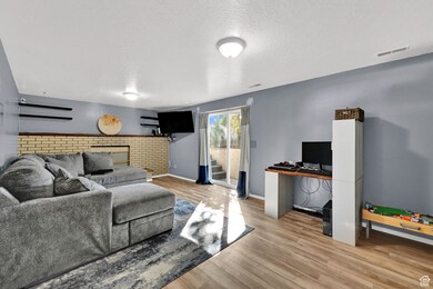 Living area featuring light wood-style floors, a textured ceiling, and a desk