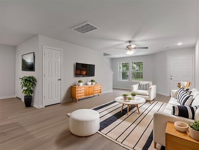 Modern living area with ceiling fan, featuring sty