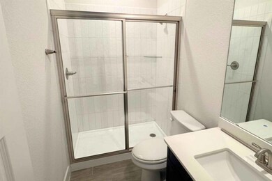 Full bathroom featuring a textured wall, vanity, and a shower stall