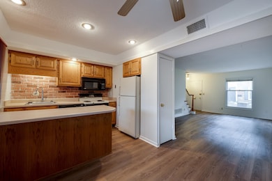 Kitchen featuring white appliances, light countertops, a ceiling fan, a textured ceiling, and wood finished floors