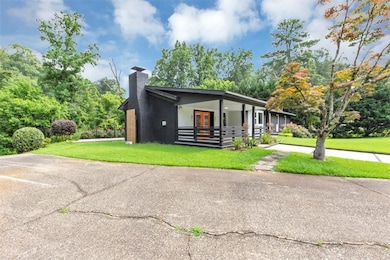 View of front of home featuring a front lawn, a chimney, french doors, and a porch