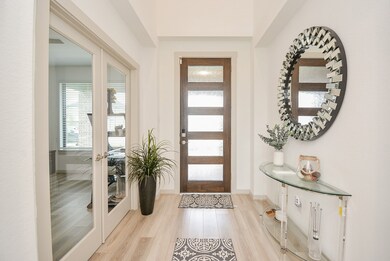 Sparkling and bright, your entrance from the inside establishes sleek, open structures that you'll see throughout; with rich, pale walls and gorgeous light laminate flooring. (The clear paned french doors, left, open onto a roomy study/home office, or perhaps a 'flex' bedroom.)