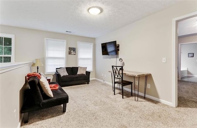 Living room with a textured ceiling, baseboards, v