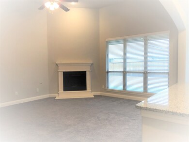 Unfurnished living room featuring dark colored carpet, a fireplace with raised hearth, a ceiling fan, and high vaulted ceiling