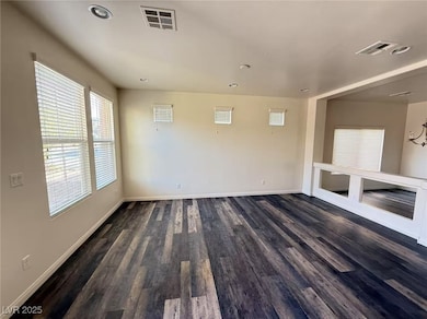 Empty room featuring baseboards, dark wood-style f