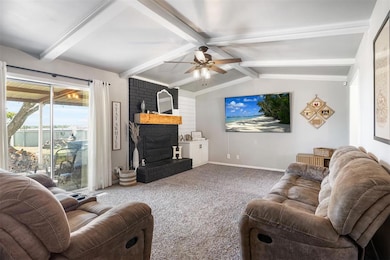 Living room with ceiling fan, carpet floors, a brick fireplace, and baseboards