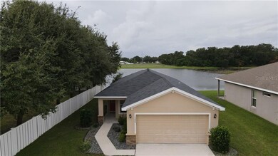 Aerial view of house with privacy fence to side, pond in back.