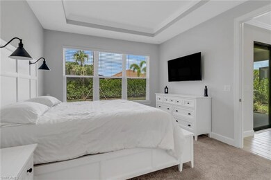 Bedroom featuring baseboards, a raised ceiling, and light carpet