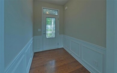 Doorway with a wainscoted wall, a decorative wall, and dark wood finished floors