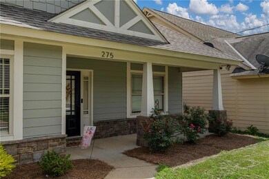 View of exterior entry featuring a shingled roof, a porch, and stone siding