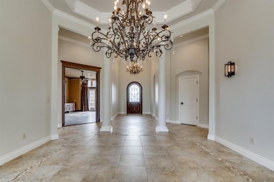 Entryway with arched walkways, a towering ceiling, crown molding, light tile patterned floors, and a ceiling fan