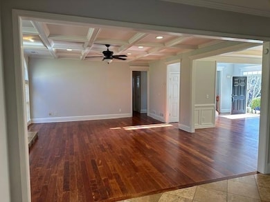 Spare room featuring beamed ceiling, wood finished floors, coffered ceiling, healthy amount of natural light, and ceiling fan