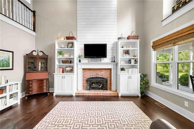 Living area featuring dark wood-type flooring, a fireplace, and a towering ceiling