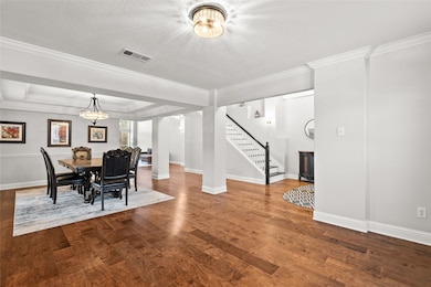 Dining space with crown molding, dark wood-style floors, and stairway