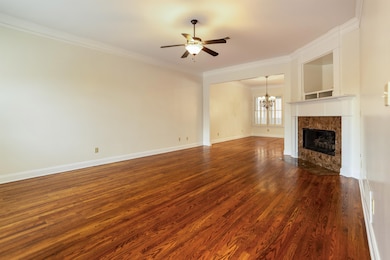 Unfurnished living room featuring a chandelier, ornamental molding, dark wood-type flooring, a premium fireplace, and a ceiling fan