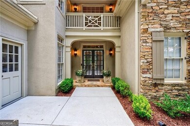 View of exterior entry with french doors, stone siding, stucco siding, and a balcony