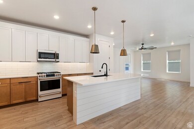 Kitchen with white appliances, decorative backsplash, white cabinets, an island with sink, and open floor plan