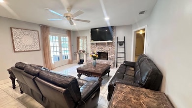 Tiled living room with a ceiling fan, french doors, a fireplace, and baseboards