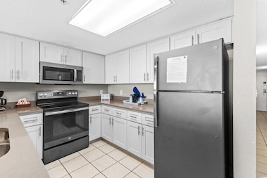 Kitchen with white cabinets, a textured ceiling, s