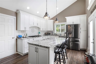 Kitchen with appliances with stainless steel finishes, backsplash, dark wood-style flooring, a breakfast bar, and recessed lighting