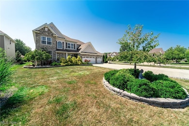 View of front of home with concrete driveway, stone siding, an attached garage, and a front lawn