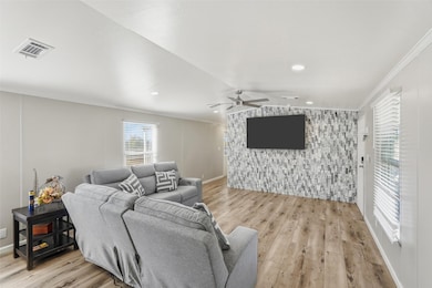 Living room with ornamental molding, light wood-type flooring, ceiling fan, and vaulted ceiling