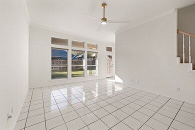Living room with crown molding, light tile patterned flooring, ceiling fan, and stairway