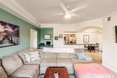 Living area featuring arched walkways, ornamental molding, and ceiling fan