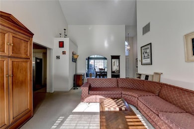 Living area featuring high vaulted ceiling and light colored carpet